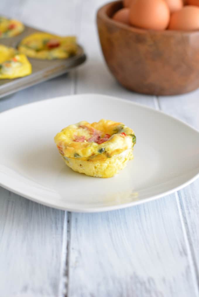 Breakfast Egg Muffin filled with roasted peppers and spinach on a white plate.