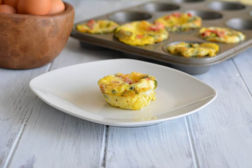 Breakfast Egg Muffin filled with roasted peppers and spinach on a white plate.