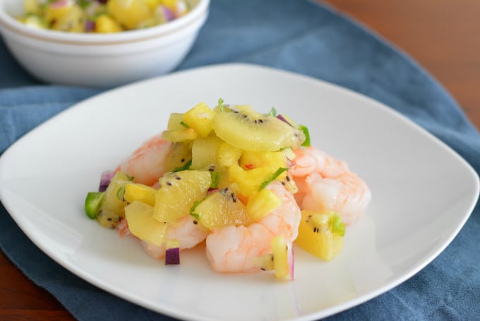 Kiwi Pineapple Fruit Salsa on top of shrimp on a white plate.